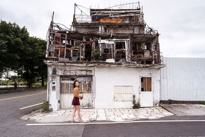 Side view of female standing on street near shabby old building located on east coast