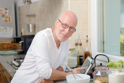 Portrait of man using laptop in kitchen at home