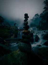 Stack of rocks in water against sky