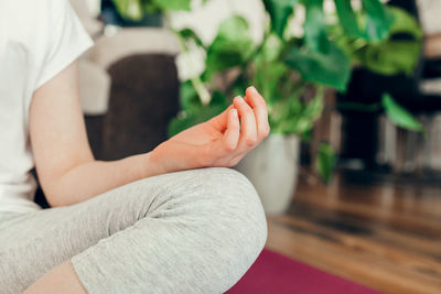 Close-up of girl's hands practicing yoga at home. a girl sits on a yoga mat in a lotus position 