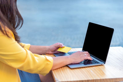 Midsection of woman using mobile phone at table