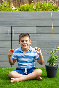 Funny boy showing tomatoes picked from the tomato plant