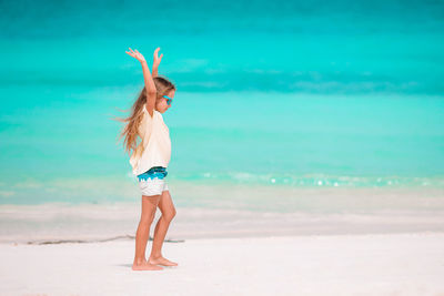 Woman with arms raised on beach