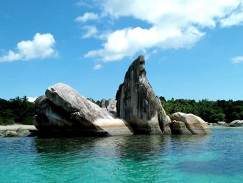 Rock formation in sea against blue sky