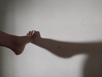 Midsection of person touching shadow on wall