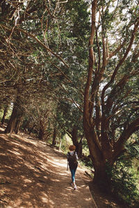 Rear view full length of woman walking by trees at park