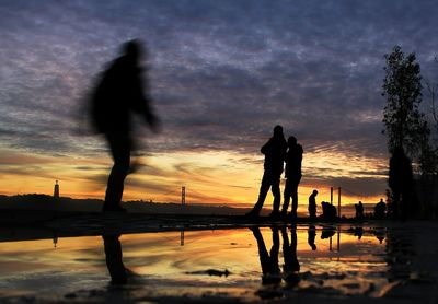 Silhouette people in swimming pool at sunset