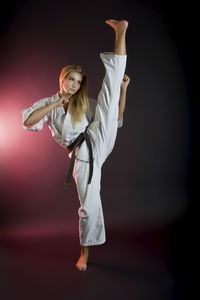 Full length of flexible woman practicing karate