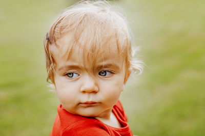 Close-up of cute baby boy looking away while sitting on field