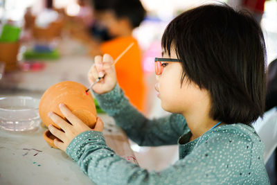 Close-up of girl painting mug at table