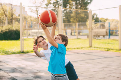 Brothers playing basketball in court