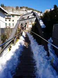 Snow covered bridge amidst buildings in city during winter