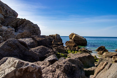 Rock formations on shore against sky