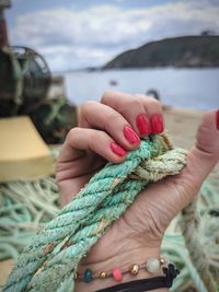 Close-up of hand holding rope over sea