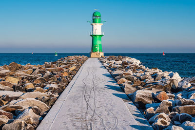 Lighthouse by sea against sky