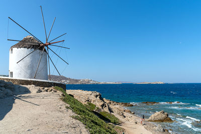 Windmill on beach against blue sky