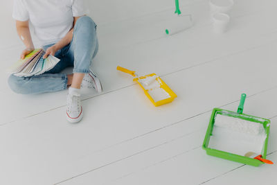 Low section of woman holding color swatches while sitting on floor at home