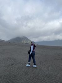 Rear view of woman walking on mountain against sky