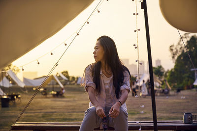 Full length of woman sitting against sky during sunset