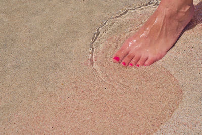 Low section of person on sand at beach