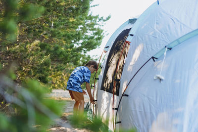 Cute little caucasian boy helping to put up a tent. family camping concept