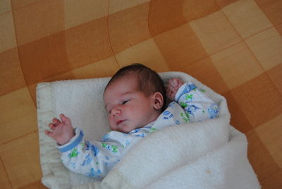 Close-up of cute baby lying on bed at home