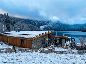 Snow covered houses by buildings against sky