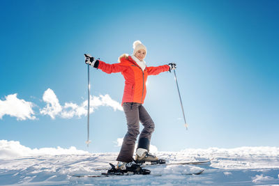 Full length of man with arms outstretched on snow against sky