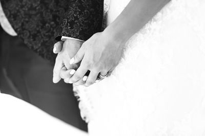 Midsection of bride and bridegroom holding hands