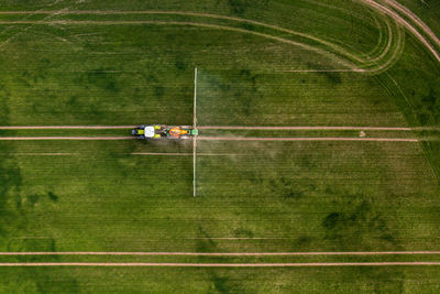 Top down view of the tractor spraying the chemicals on the large green field, agriculture concept