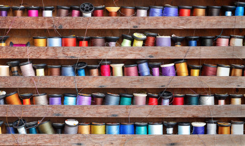 Full frame shot of multi colored spools of threads in shelves