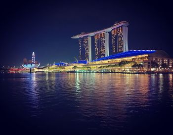 Illuminated building by river at night