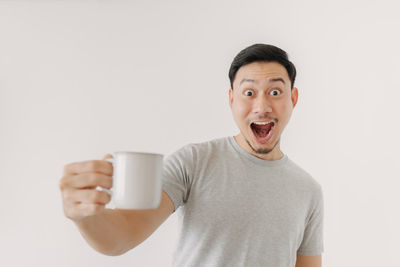 Portrait of man drinking coffee cup against white background