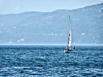 Sailboat moving on river against mountain