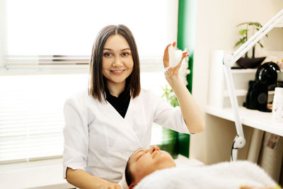 Portrait of a beautician girl with a gouache scraper in her hand while working in a cosmetology