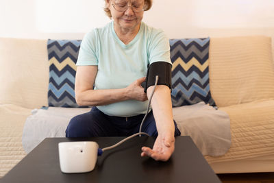 Young woman using mobile phone while sitting on sofa at home