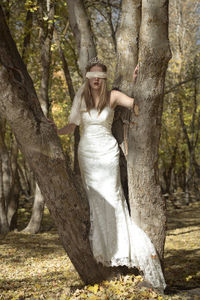 Bride standing on tree trunk in forest