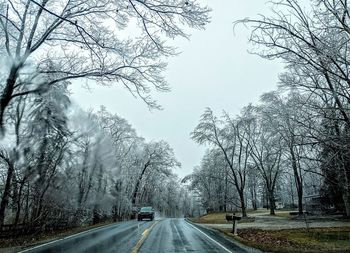 Road amidst bare trees against sky