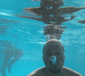 Portrait of shirtless man swimming in pool