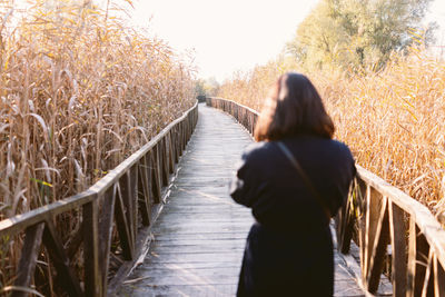 Rear view of woman walking on boardwalk