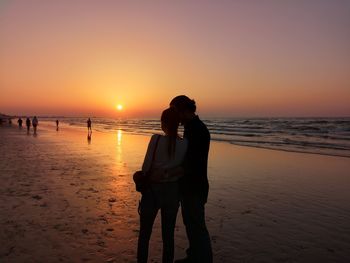 Man standing on beach against sky during sunset