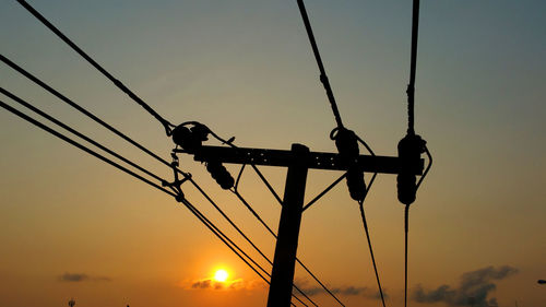 Low angle view of silhouette electricity pylon against sky during sunset