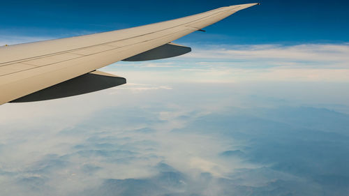 Wing of plane over white clouds. airplane flying on sunrise sky. scenic view from airplane window. 