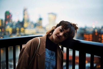 Portrait of man leaning on railing in city