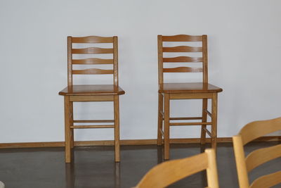 Empty chairs and table against wall