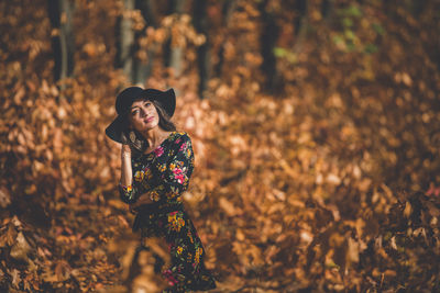 Young woman wearing hat standing amidst plants in forest