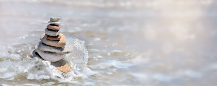 Heap of pebbles in balance on the sea background and splash with copy space in the right