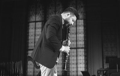 Man playing clarinet while standing at studio