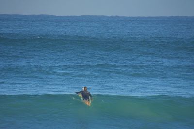 Man surfing in sea against sky