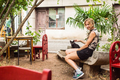 Full length of girl using phone while sitting on tree